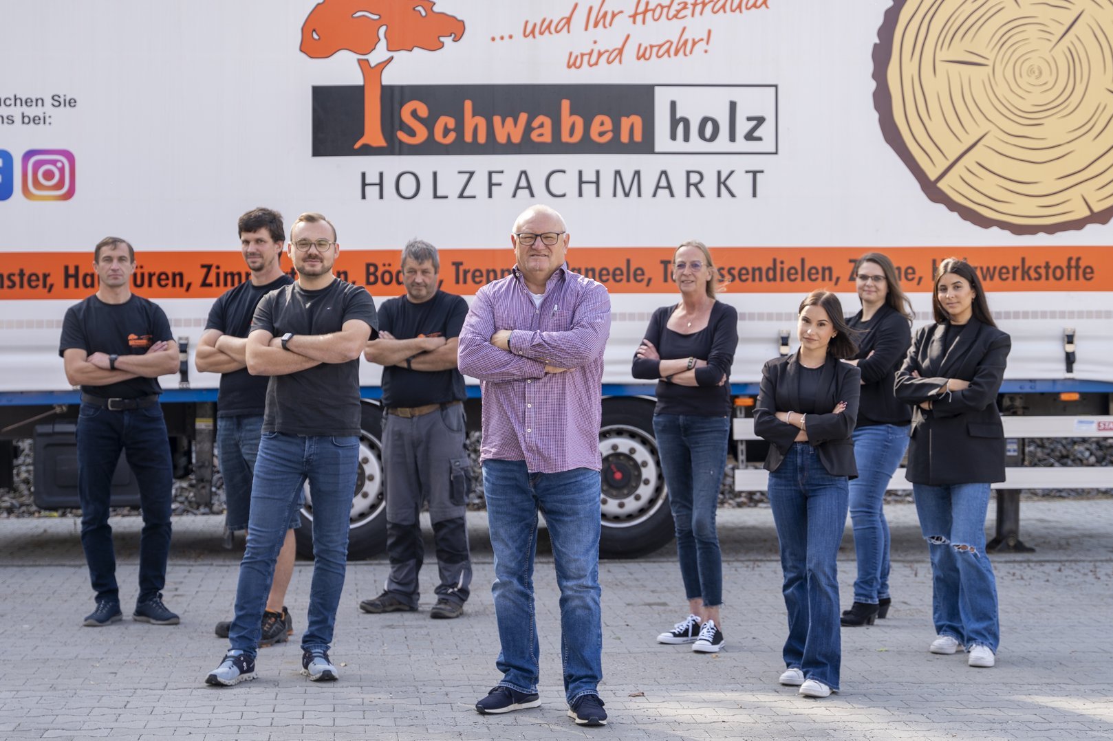 Eine Gruppe von neun Mitarbeitenden von Schwabenholz steht vor einem LKW mit dem Firmenlogo. Sie posieren mit verschränkten Armen und wirken professionell und geschlossen.